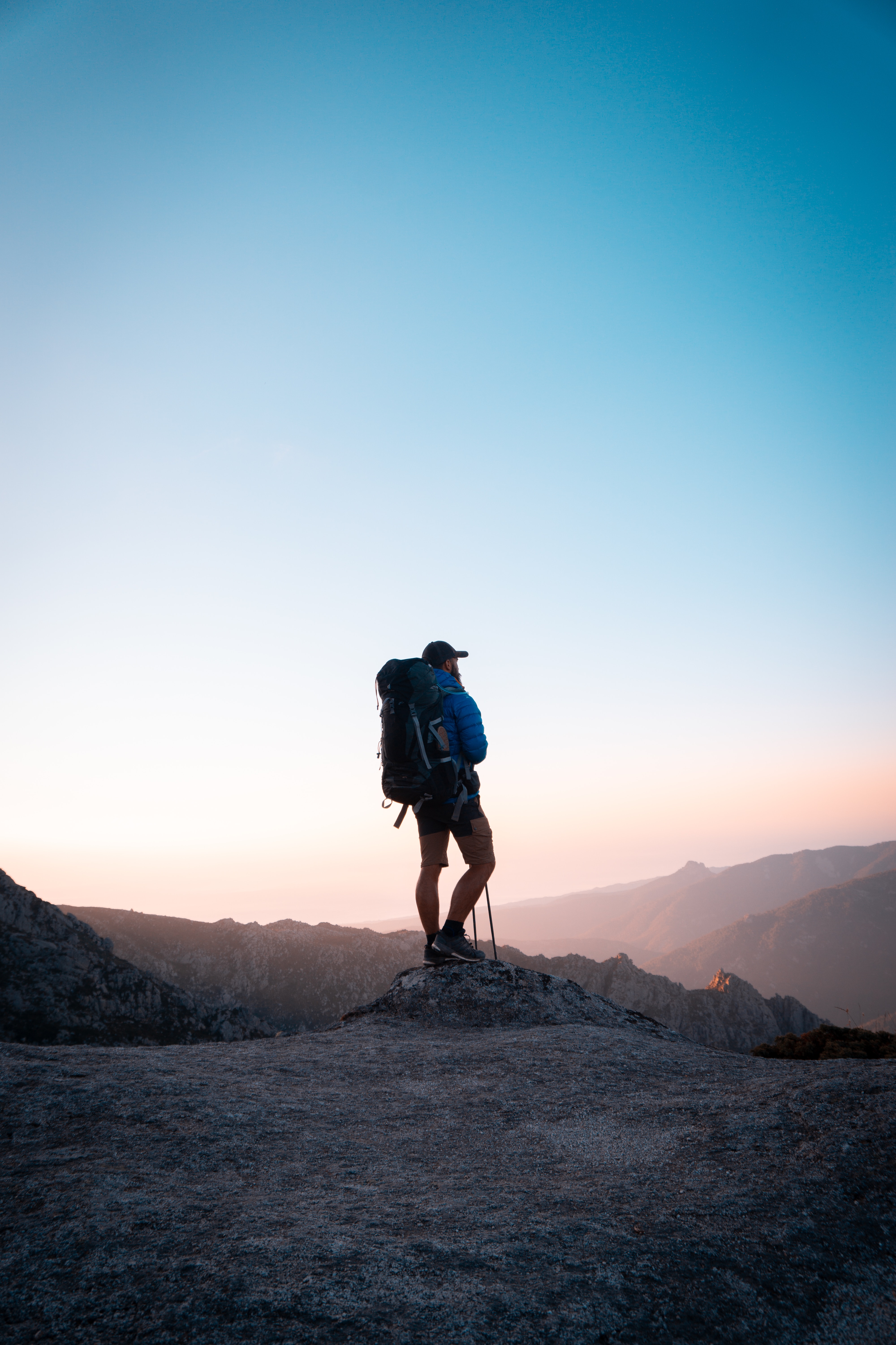 Person with walking sticks watching sunrise on mountain