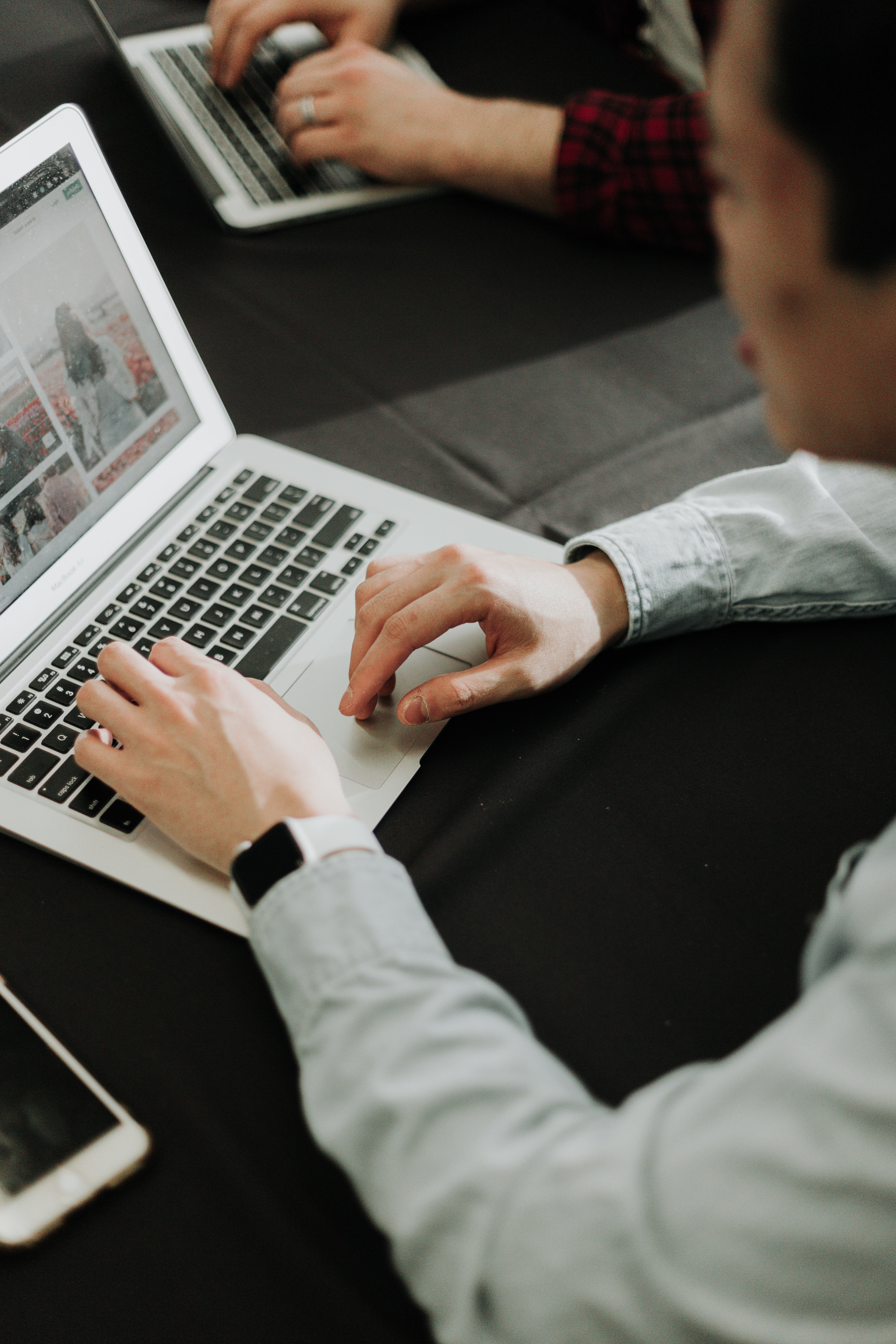 Person working on laptop with digital arm watch