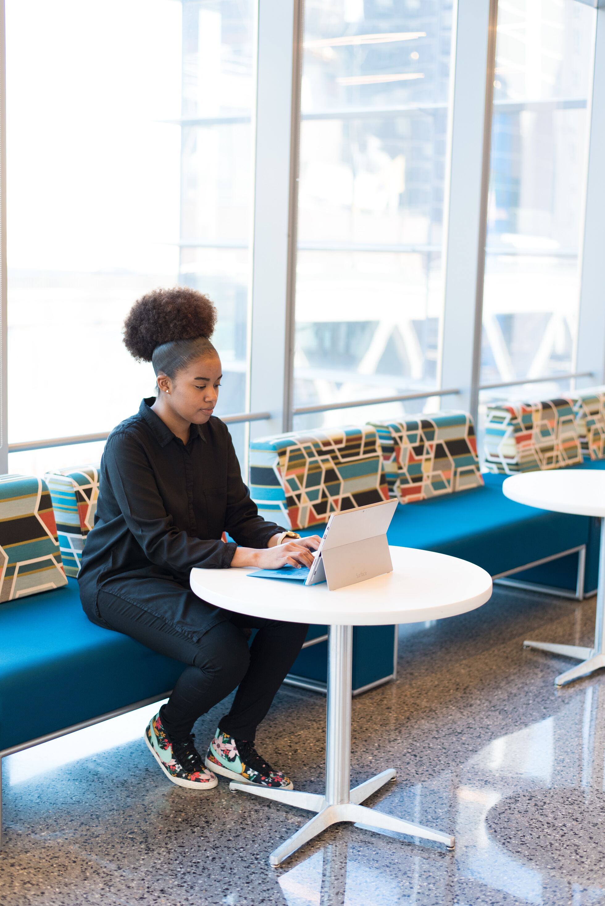 woman sits on sofa while using laptop